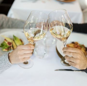 close up of couple clinking wine glasses in a restaurant