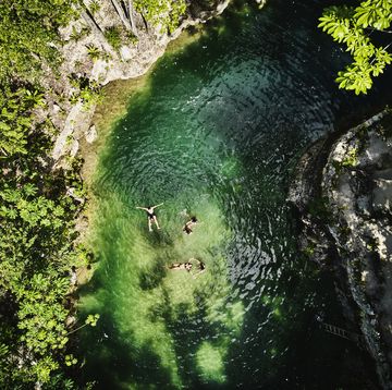 extreme wide shot aerial view of friends relaxing in cenote at eco resort in jungle